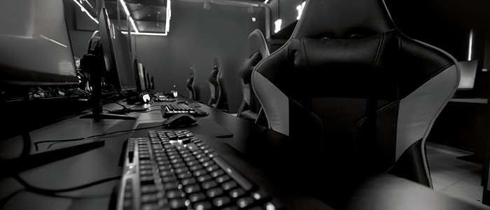 A row of gaming chairs sit empty in front of keyboards and screens.
